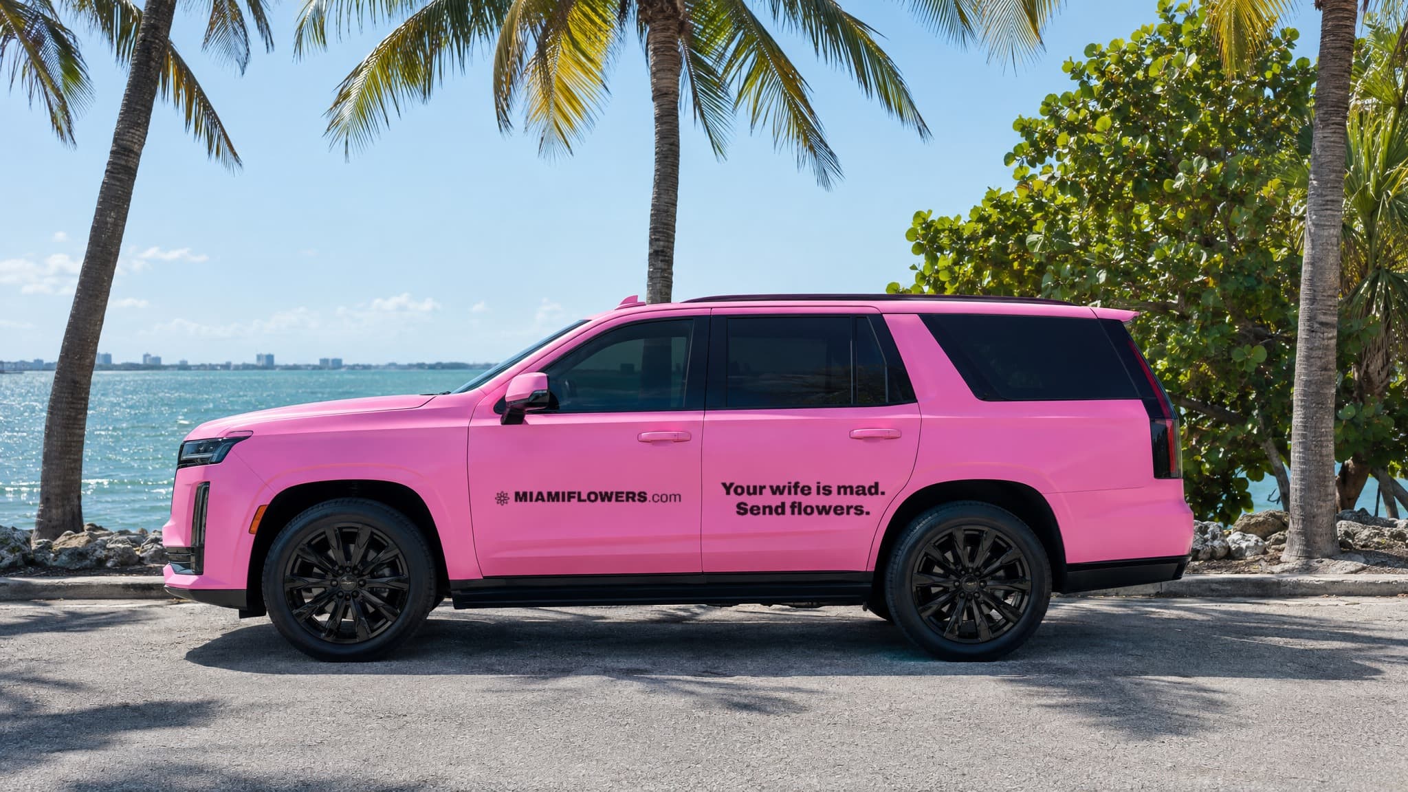 Pink MIAMIFLOWERS.com Escalade on Key Biscayne reading 'Your wife is mad. Send flowers.'