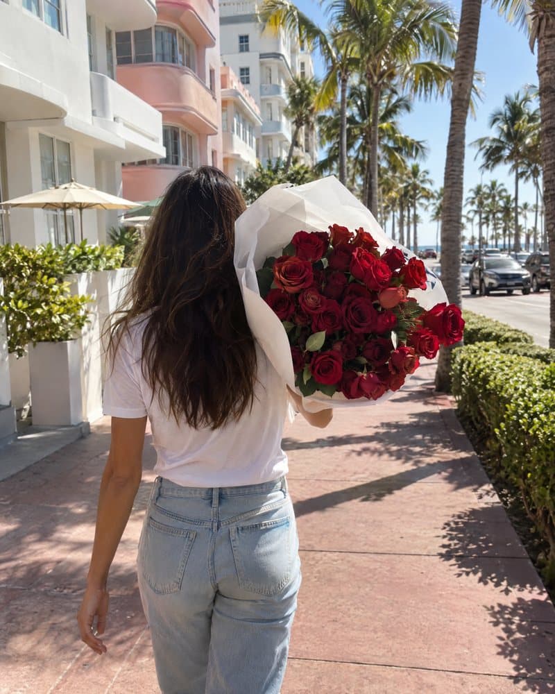 Woman carrying red roses over her shoulder on a Miami Beach sidewalk
